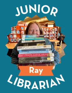 person peeking up from a stack of books junior librarian ray